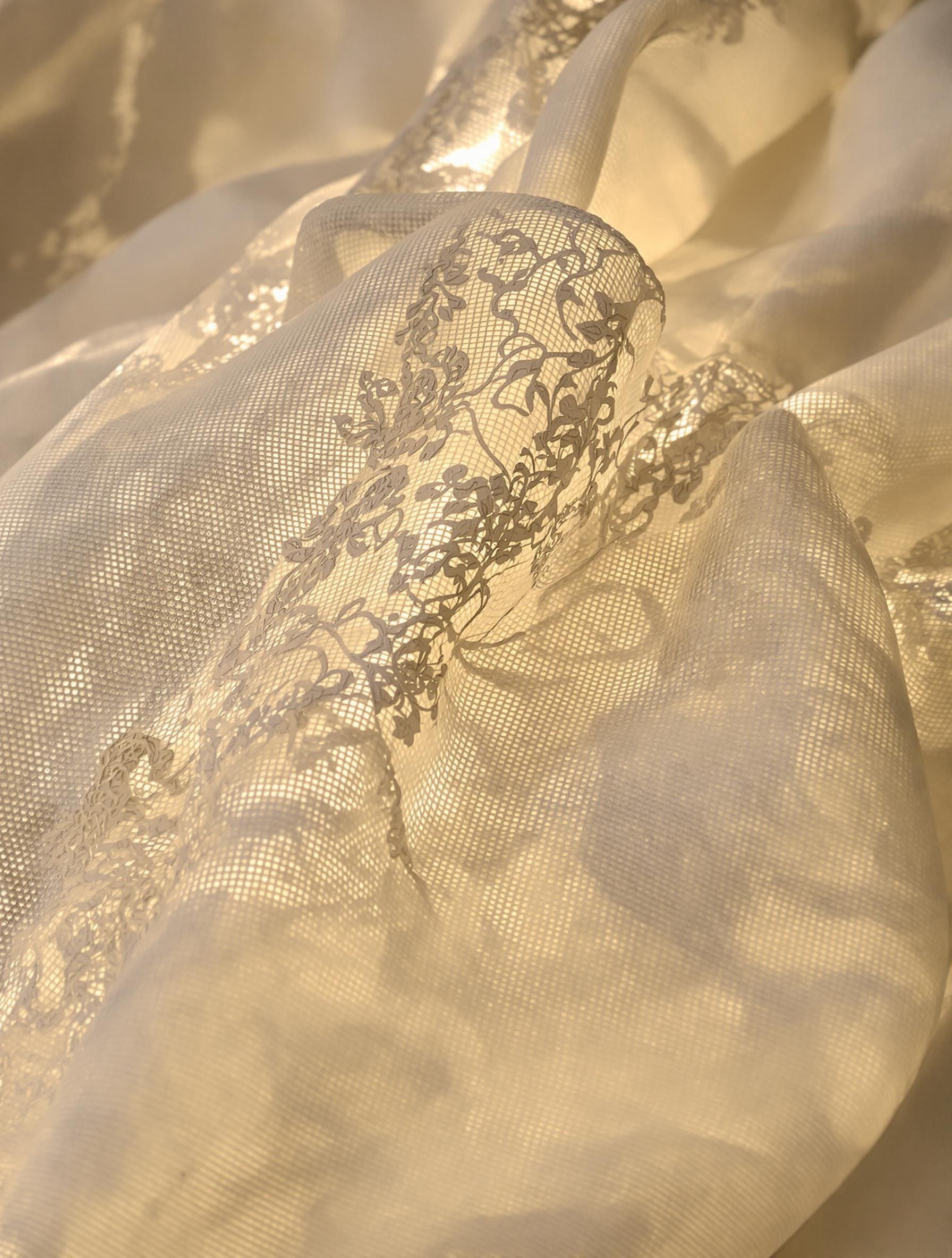 Gros plan sur un lin texturé, dentelle fine brodée et organza, ambiance artisanale Printemps/Été 2025.